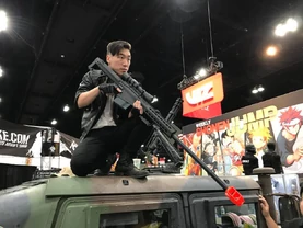 D with a Airsoft sniper rifle at a TAC-City show floor