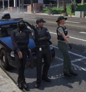 Mr K, Tessa and Suarez in front of a cop car