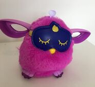 A magenta Furby Connect with its sleep mask on