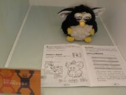 A Black Furbish behind a Chinese 2005 Furby's manual.