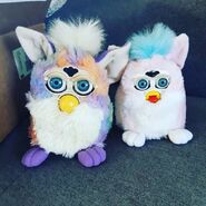 A Tie Dye Furby next to Baby Pink Furby Baby