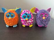 An Orange Orangutan Furby with a Pink Cubes Furby Boom and a Voodoo Furby.