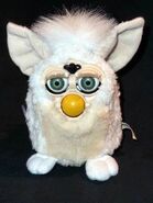 A lamb Furby with green eyes.