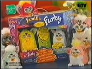 An adult and baby Furby packaged together as a set called "La famiglia Furby" with other Furbys near it. This screenshot was from an Italian advertisement.