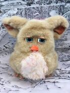 A Sand Emototronic Furby with a worn beak