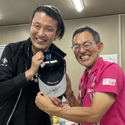 Fujishima (left) posing with an autograph from former Gran Prix motorcycle racer Noboru "Nobby" Ueda (right) in 2023