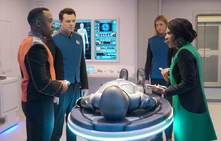 The crew discusses 's treatment in Sick Bay. Note that behind 's shoulder is a molecular-resolution scanner display.