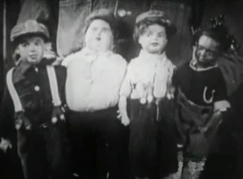 Dolls resembling Mickey, Joe, Jackie, and Farina.  They are being held by Mary's garderner.