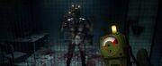 The witness (A man in just his underwear and a bomb helmet strapped to his head with three yellow blinking lights) in a cell watching a hand use the microwave trigger.