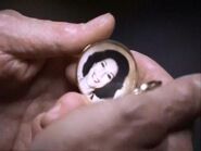 Nino holding a locket with a photo of Angie inside.