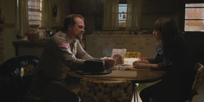 In the kitchen, Joyce talks to Hopper.