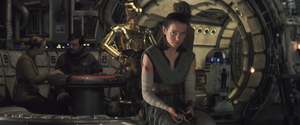 Rey thoughtful while holding the broken pieces of the Skywaker lightsaber.