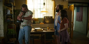 Joyce and Murray watching Hopper relay a message to Owens about the Russians opening a gate to the Upside Down at Starcourt Mall.