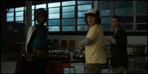 Lucas, Dustin, and El being alerted by Mike that the government agents have arrived at the school.