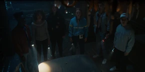 Lucas and the others watching a chandelier's lights flicker on their own.