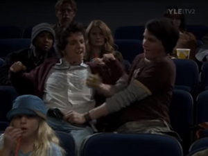 Jasper and Fred in the movie theatre getting snacks hidden in Jasper's pants