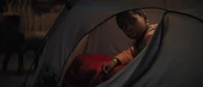 Travis in a tent after being forced by the mansion's ghosts to return.