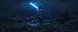 Rey holds the saber against Luke