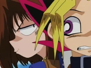 Téa whispering to Yugi to duel Mai