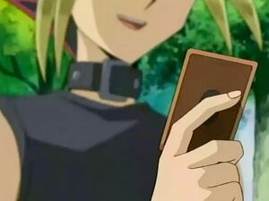 An adult Yugi Muto giving Jaden Yuki the Winged Kuriboh card