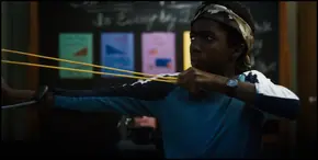 Lucas firing a rock at the Demogorgon with his slingshot.