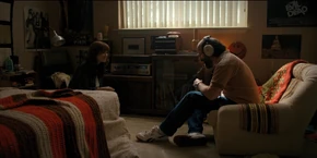 Joyce and Murray sitting in Jonathan's room as they use his radio to listen to the tape to hear what the woman is saying to Enzo.