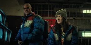 Joyce and Hopper glancing at each other as Murray translates Melnikov explaining how the Demogorgon broke into the control room and caused a commission that freed the demodogs.