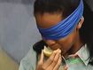 Keesha wears a blindfold as she eats a lemon