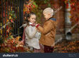 Stock-photo-the-boy-is-holding-the-hands-of-the-grapes-and-the-girl-is-sitting-in-the-autumn-park-walking-in-704114590