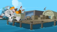 The puppet tackles Dennis' mech into the water.