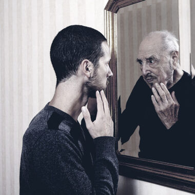 a young man looking into a mirror only to see an older version of himself staring back at him.