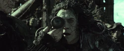 Salazar looks through his spyglass from his cursed ghost ship at Jack Sparrow on a longboat near Hangman's Bay.
