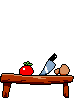 A wooden table with a tomato, knife and mushroom on it.