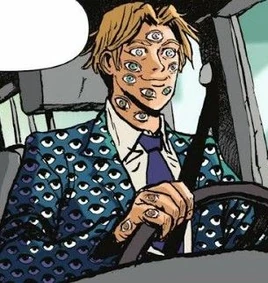 Prowadzący samochód Argus ubrany w niebieską marynarkę pokrytą gałkami ocznymi założoną na białą koszulę z wiszącym pod szyją granatowym krawatem