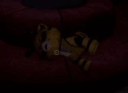 Un juguete ensangrentado de Cat-Bee en el sofa al lado de la puerta cerrada.