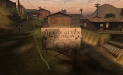 A Chicken Queen Estates signpost with various houses in the background.