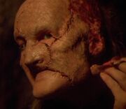 Destler applying flesh pieces to his face.
