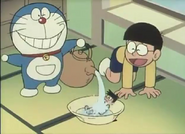 Doraemon (Doraemon) remotely tormenting Suneo by pouring water onto his voodoo doll, making it look like he's wetting his pants nonstop, causing him public humiliation.