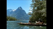 Two Māori drifing down a river in a canoe.