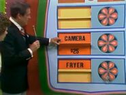 She keeps the camera. The spice rack is $25 and goes into the give column for a total of $58.