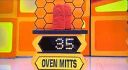 She bids $25 on the oven mitts. A difference of $10. She picks card #5.