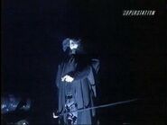 A mysterious black hooded man points to Vampiro.