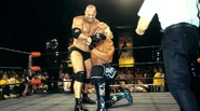 Goldberg puts Hulk Hogan in a headlock.