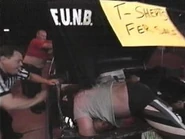 Funk trashes the table as he gets yelled at by Norman Smiley.