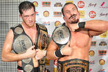 Bobby Fish and Kyle O'Reilly, two black-haired Caucasian men in black reDRagon T-shirts with the ROH World Tag Team Championship belts