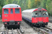 Metropolitan Line A60/62 Stock departing Rayner's Lane on an Uxbridge Service with a Piccadilly Line 1973 Tube Stock train remaining idle in the siding.