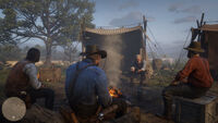 Gang members sharing stories with one another at the campfire. From left to right, John Marston, Arthur Morgan, Hosea Matthews and Uncle