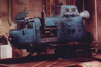 Blue Midget in the Red Dwarf hangar bay, resting on caterpillar tracks