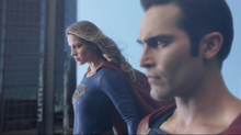 Supergirl e Superman voando juntos em National City.