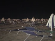 A creepy beach at night with lawn chairs and umbrellas[5]